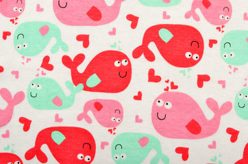 Cute fabric for kids with many beluga fish. Many pink and green fish with hearts on white as background.