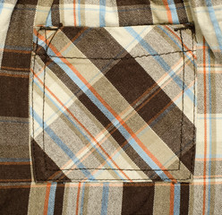 Pocket on pants with scottish tartan pattern. Brown with red and blue plaid print as background.