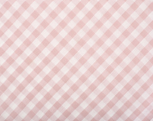 Close up on checkered tablecloth fabric. Pink with white tartan square pattern as background.