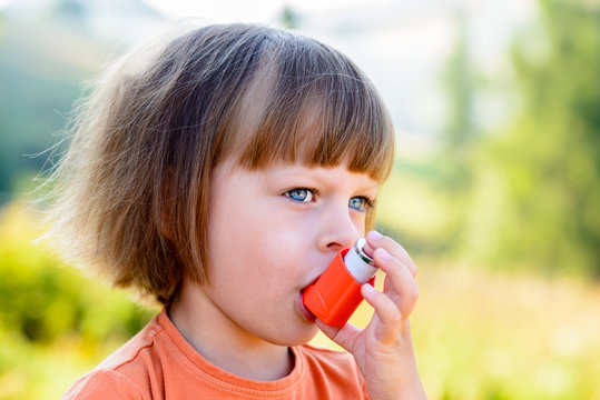 Little girl using inhaler on a sunny day - shallow depth of field