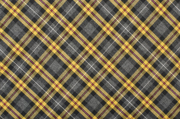 Scottish tartan pattern. Yellow with grey and black plaid print as background. Symmetric rhombus pattern.