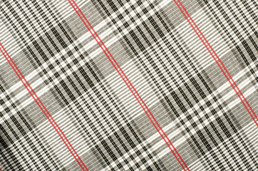 Scottish tartan pattern. Red with white and black plaid print as background. Symmetric rhombus pattern.