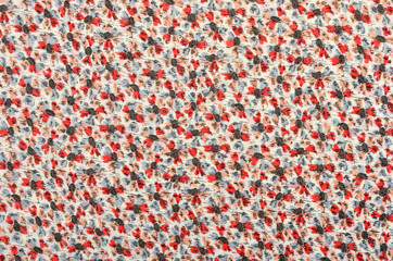 Small floral pattern on fabric. Red and gray flowers print as background.