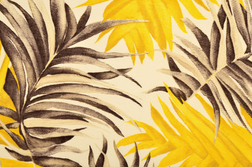 Tropical brown and yellow leaves pattern on fabric. Palm leaves print as background.