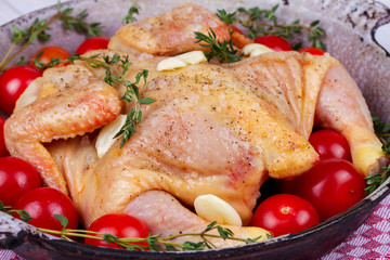 Whole fresh raw chicken prepared for roast with thyme and tomatoes cherry