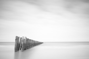 Black and white fine art landscape of the sea with wooden poles