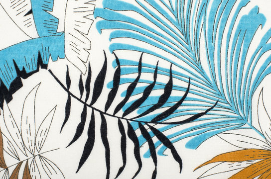 Tropical leaves pattern on white fabric. Black with blue and brown palm leaves print as background.