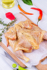 Whole fresh raw chicken prepared for roast with thyme and tomatoes cherry