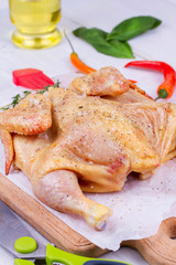 Whole fresh raw chicken prepared for roast with thyme and tomatoes cherry
