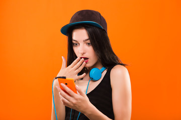 Surprised young brunette woman holding smart phone in her hand