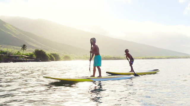 Family Stand Up Paddling on Sunny Blue Sky Morning Sunrise in Hawaii. Summer Fun Family Vacation Healthy Lifestyle. Learning to Surf. SUP.