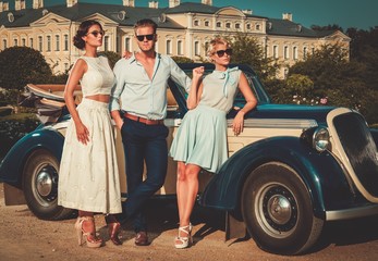 Wealthy friends near classic convertible