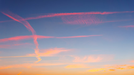cloudscape with airplane trails at sunset