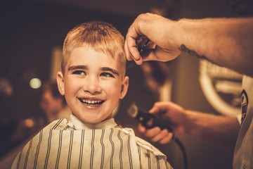 Little boy visiting hairstylist in barber shop