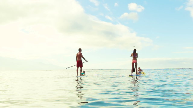 Family Stand Up Paddling on Sunny Blue Sky Morning Sunrise in Hawaii. Summer Fun Family Vacation Healthy Lifestyle. Learning to Surf. SUP.