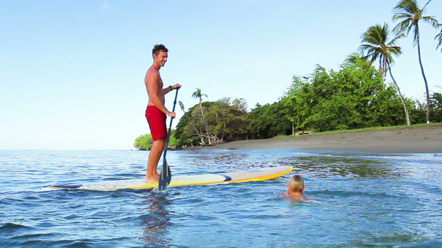 Young Boy Jumps off Stand Up Paddle Board with his father. Summer Fun Family Vacation Healthy Lifestyle. Tandem SUP.
