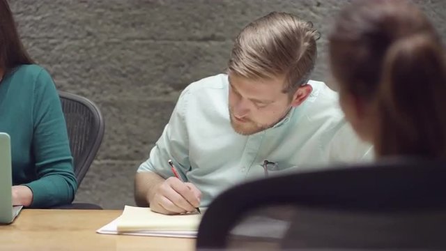 Man listening and taking notes in a small business meeting