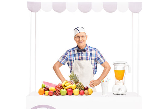 Soda jerk standing behind a stand full of fruits