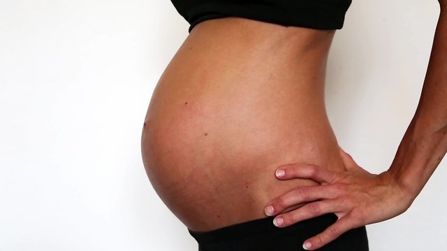 eine schwangere Frau bekommt das Symbol f&uuml;r weiblich auf den Bauch gemalt