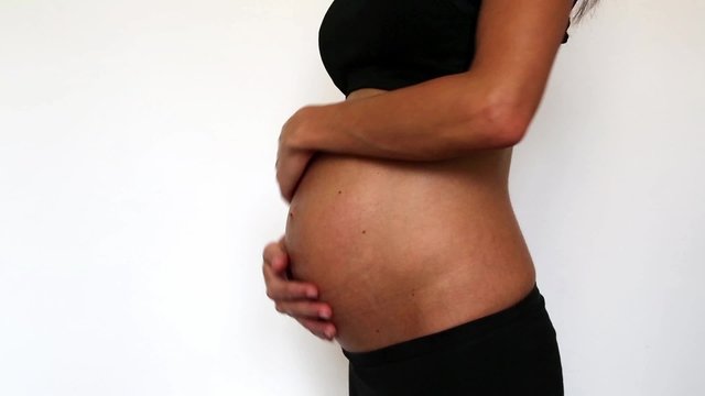 eine schwangere Frau reibt sich ihnen Bauch