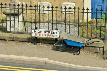 Welsh High Street sign - Stryd Fawr - with blue wheel barrow and iron railings. 