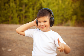 Boy in big headphones listening to music in the forest outdoors