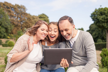 Beautiful girl is showing tablet to her old parents