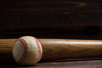 A wooden baseball bat and ball on a wooden background