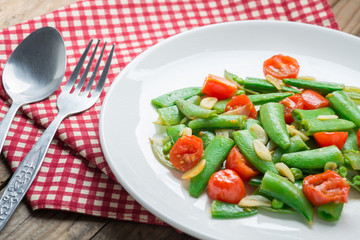 Stir fry sugar snap peas with tomato.