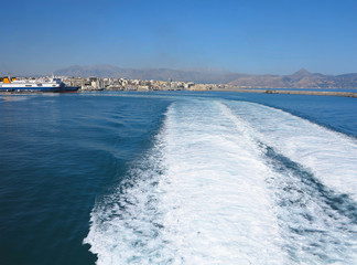 Trail on water surface behind of fast moving ferryboat