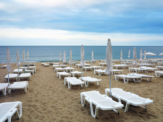 Beach chairs and umbrella on the sand near sea, blue sky