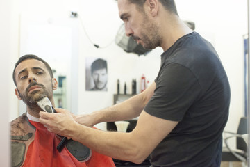 Parrucchiere esegue taglio alla moda su un cliente