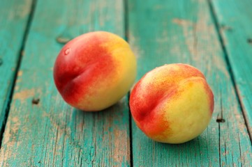Two fresh ripe whole nectarines on vintage turquoise table