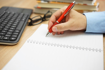 office work, businessman hand is writes  in a notebook with book