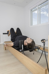 Man doing pilates in reformer bed