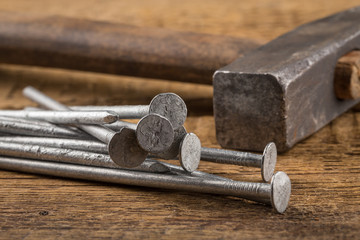 Vintage hammer with nails on wood background