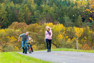 Vater zeigt Tochter Fahrradfahren bei Familien Spaziergang im Herbst Park 