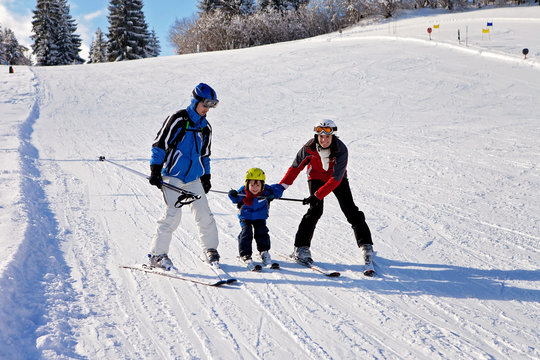 Beautiful young mom, dad and their toddler boy, skiing in the mo