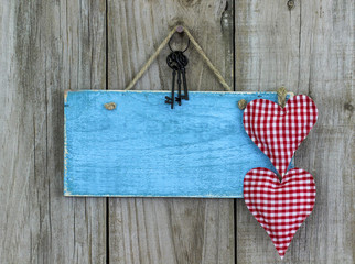 Blank blue sign with keys and hearts hanging on rustic wood background