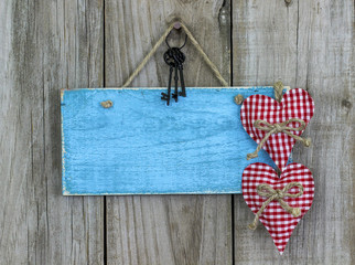 Blank blue sign with keys and hearts hanging on rustic wood background