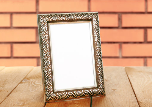 Old empty frame standing on table on brick wall background