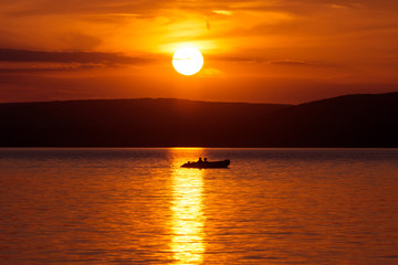 Inflatable boat floating on the water in sunset glare