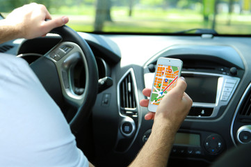Man sitting in the car and holding smart phone with map gps navigation application