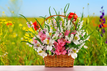 Fototapety  Piękne polne kwiaty w wiklinowym koszu na tle pola