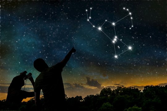 Orion constellation on night sky. Astrology concept. Silhouettes of adult man and child observing night sky.