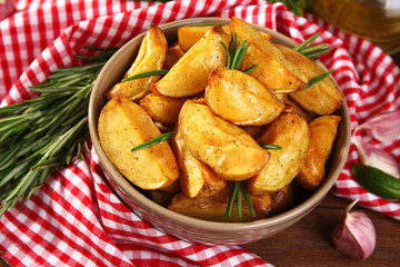 Baked potato wedges on wooden table, closeup