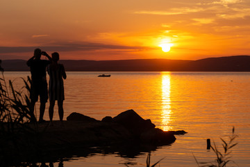 Tourists photographing the sunset on Balaton with a rubber boat