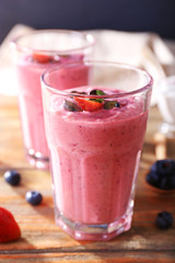 Glasses of berry smoothie on wooden table, closeup