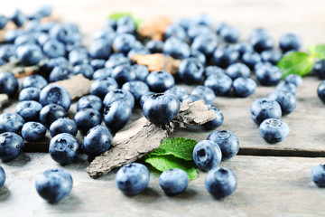 Tasty ripe blueberries with green leaves on wooden table close up