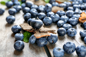 Tasty ripe blueberries with green leaves on wooden table close up